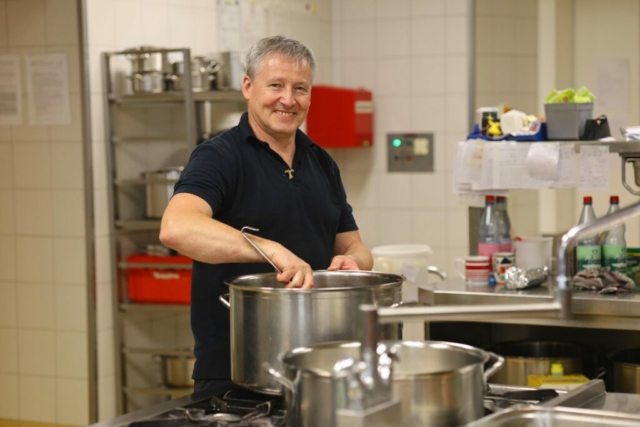 Küchenchef in der Großküche gut gelaunt, freut sich über familienfreundliche Arbeitszeiten und ein nettes Team.