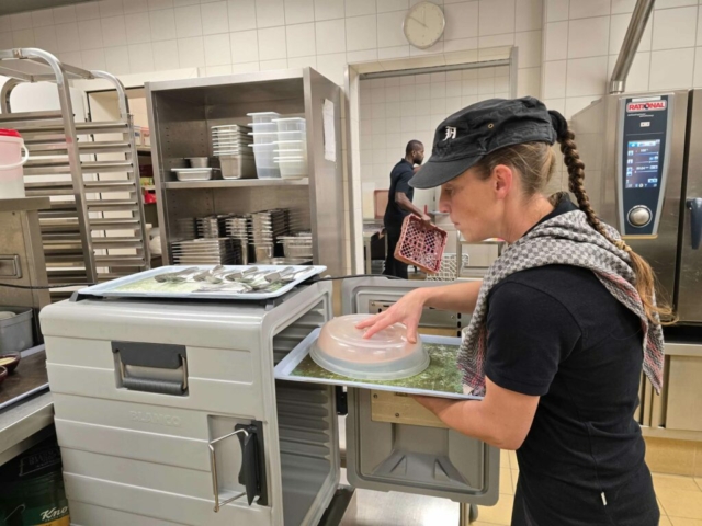 Köchin schiebt die angerichteten Essen in Warmhalteboxen, damit die Bewohnerinnen im Pflegeheim Antoniushaus stets warmes Essen bekommen.