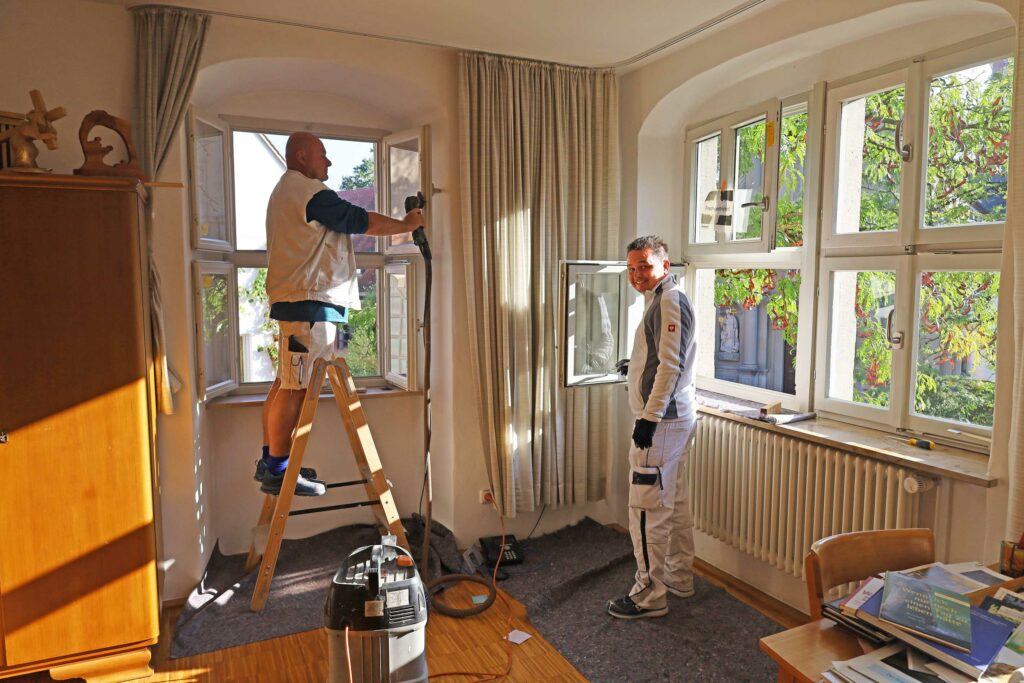 Zwei Maler streichen Fenster im Kloster