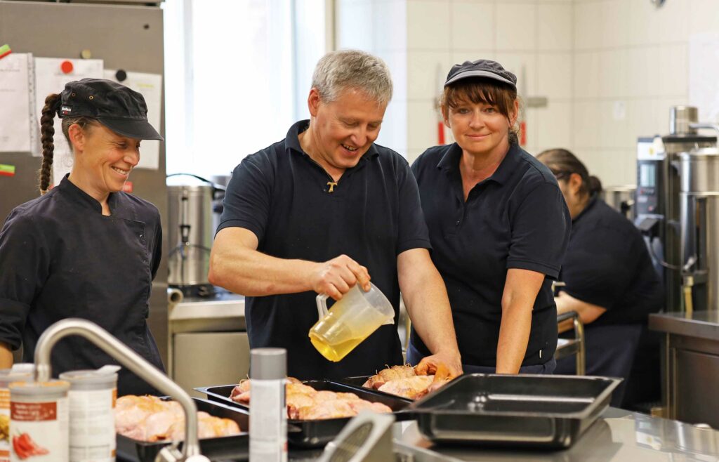 Teamarbeit mit zwei Köchinnen und einen Koch.