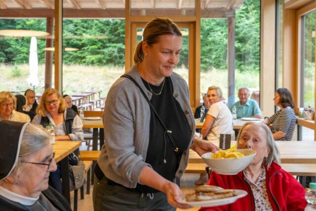 Einrichtungsleiterin Stephanie Kraus verteilt Bratwürste und Pommes an die Ausflügler.