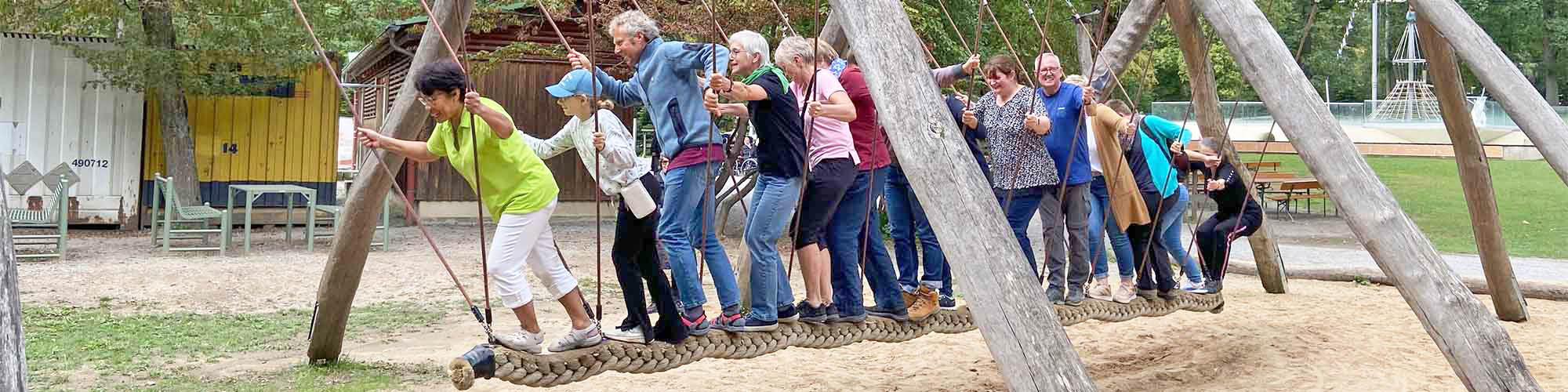 Menschen jeden Alters versuchen gemeinsam Gleichgewicht zu halten.
