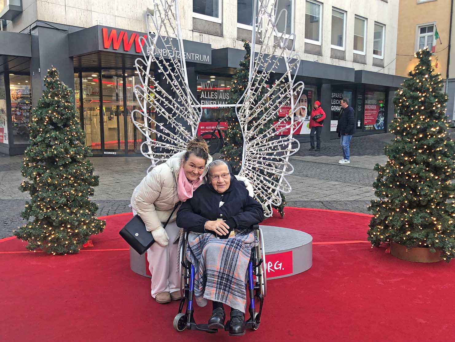 Schwester mit Begleiterin vor Engelsflügeln